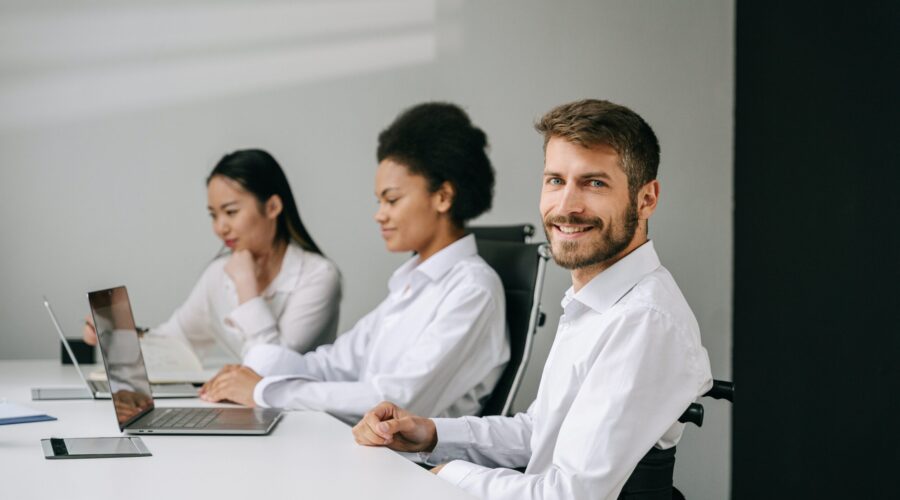 A man is smiling at his office job because not only does he have a group life insurance policy from his job, he also has an individual policy that allows him many more benefits.